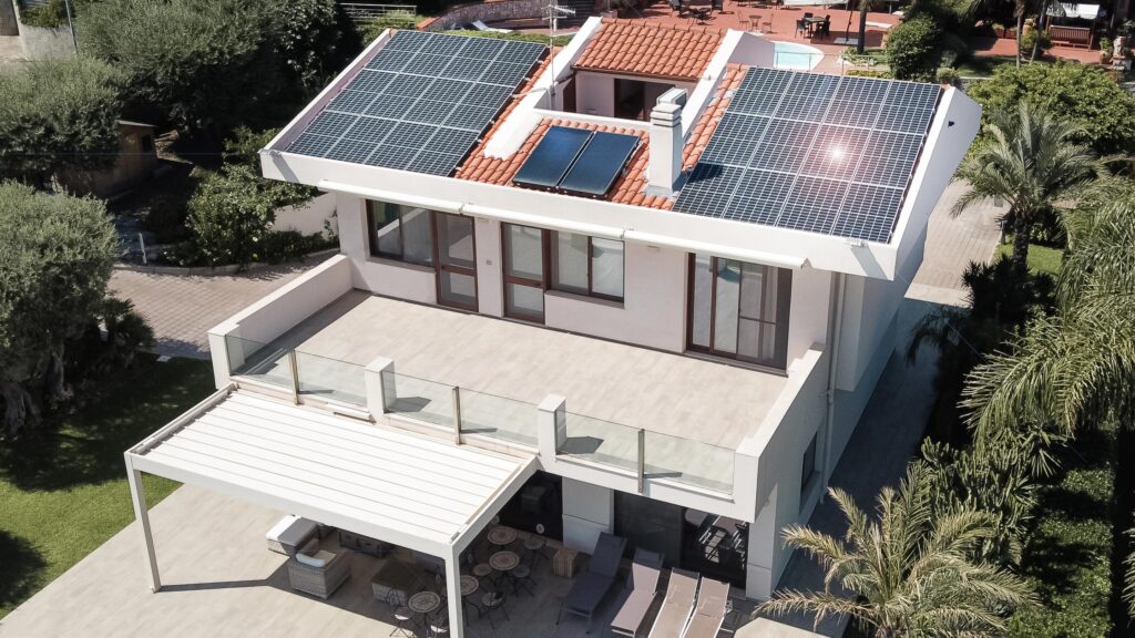 casa con pannelli fotovoltaici, tenda e piscina nel giardino